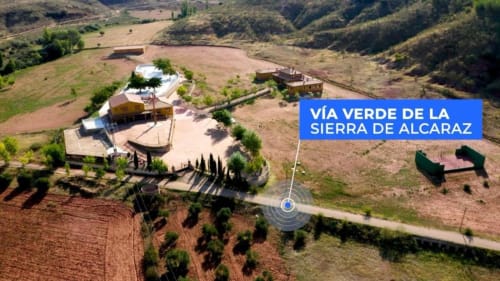 Vista aérea de la villa Finca El Arroyo en Alcaraz con terraza, patio y tierras de cultivo adyacentes a la Vía Verde de la Sierra.