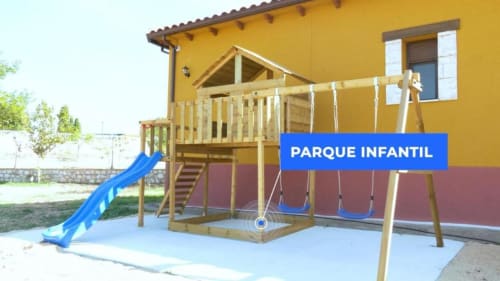 Colorido parque infantil con tobogán, columpios y estructura de madera en la villa Finca El Arroyo de Alcaraz