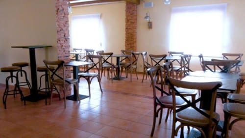 Luminoso comedor y salón en la villa Finca El Arroyo de Alcaraz con mesas de madera, sillas de respaldo cruzado y grandes ventanales