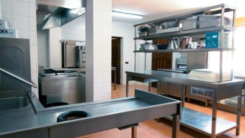 Cocina profesional en villa Finca El Arroyo, Alcaraz, con mesas de preparación de acero inoxidable, estanterías y equipamiento de grado comercial