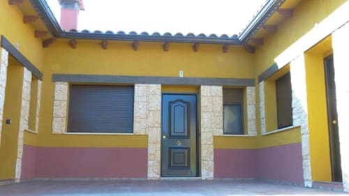 Entrada de la villa Finca El Arroyo en Alcaraz con muros amarillos, puerta azul y patio cubierto