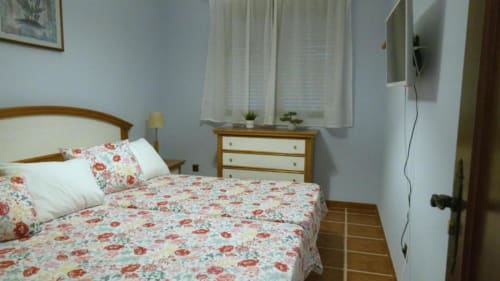 Habitación luminosa en la villa Finca El Arroyo, Alcaraz, con ropa de cama floral, muebles de madera y TV de pantalla plana