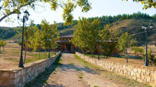 Entrada de la villa Finca El Arroyo en Alcaraz: senderos de piedra, arquitectura tradicional y entrada arbolada