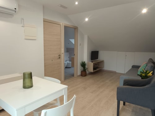 Interior moderno del apartamento Avio en Santiago de Compostela con sala de estar, zona de cocina, sofá y detalles en madera