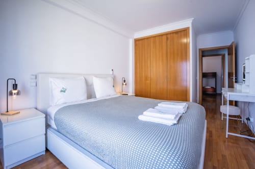 Modernes Schlafzimmer im EcoHost OceanLeaf Apartment in Matosinhos mit Doppelbett, Holzgarderobe und Gartenterrasse mit Meerblick