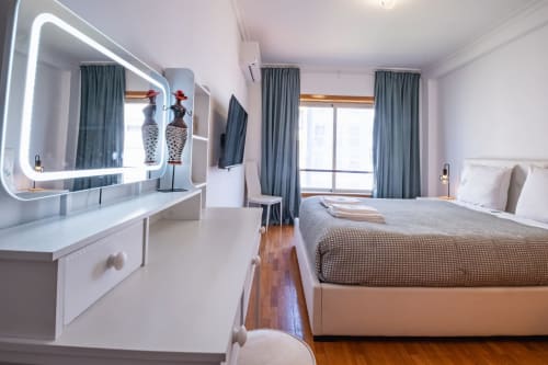 Modernes Schlafzimmer im EcoHost Matosinhos mit neonbeleuchteter Frisiertisch, Queensize-Bett, grauen Vorhängen und Parkettboden