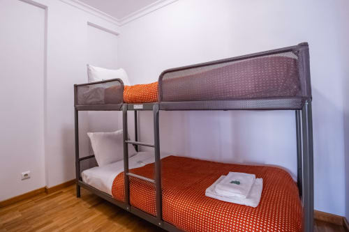 Modernes Etagenbett mit orange-weißer Bettwäsche in hellem Schlafzimmer der EcoHost Wohnung in Matosinhos