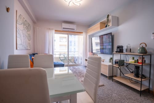Modernes Wohnzimmer im OceanLeaf Apartment in Matosinhos mit beigem Mobiliar, TV, Kochnische und Balkonzugang