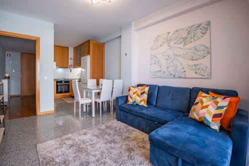 Séjour moderne avec canapé bleu, espace repas, cuisine en bois et œuvre d'art botanique à EcoHost Matosinhos