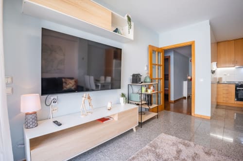 Modernes Wohnzimmer im OceanLeaf Apartment, Matosinhos, mit Wandfernseher, Holzmöbeln und orangefarbenen französischen Türen