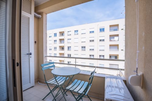 Privater Balkon mit blauen Stühlen und Tisch mit Blick auf Apartmentgebäude in Matosinhos im EcoHost Hotel