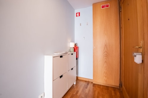 Flureingang des EcoHost Matosinhos Apartments mit weißen Wänden, Holztüren, Brandschutzausrüstung und Schuhregal