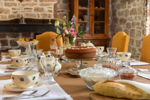 Table de petit-déjeuner élégante à La Demeure du Comte B&B à Marcillac-Vallon avec viennoiseries, service à thé et fleurs fraîches