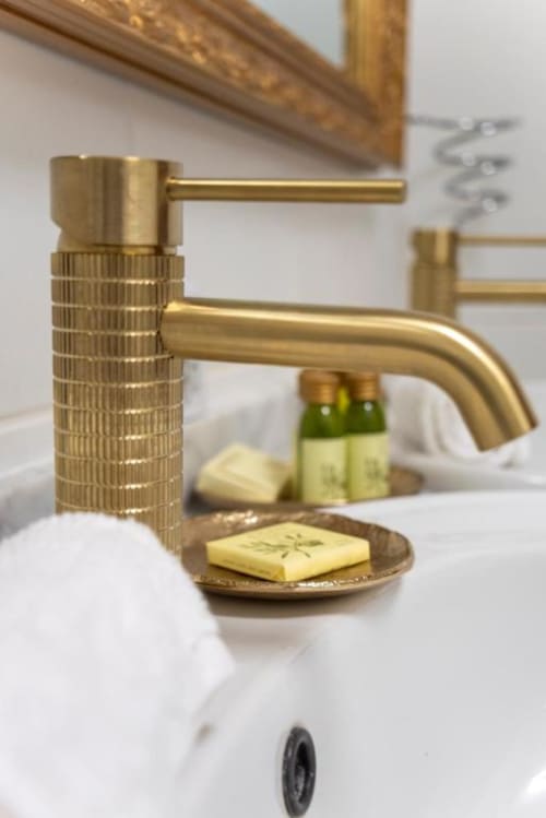 Robinet de salle de bain en laiton luxueux avec poignée texturée à La Demeure du Comte, accompagné de savon et produits de toilette