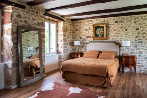 Chambre rustique en pierre à La Demeure du Comte à Marcillac-Vallon avec poutres apparentes, parquets et mobilier douillet.