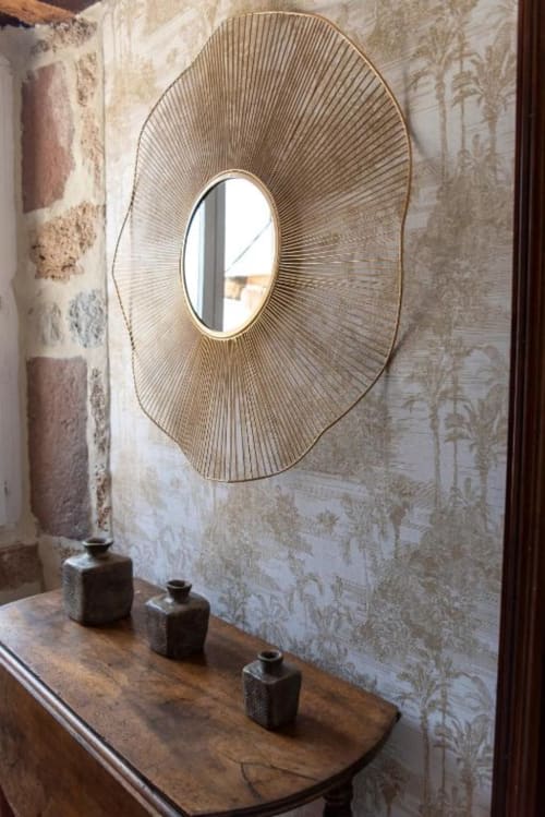 Élégant miroir ovale en forme de soleil au-dessus d'une console en bois avec des vases décératifs dans la chambre de la Comtesse à La Demeure du Comte,