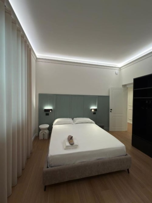 Camera moderna della Maison Riviera B&B a Reggio di Calabria con letto queen size, testata turchese, luci ambient e bianco