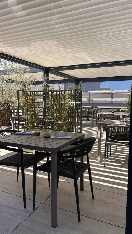 Espace de restauration moderne à la terrasse de l'Hôtel Restaurant Le S'Y à Seingbouse avec mobilier noir sous pergola blanche