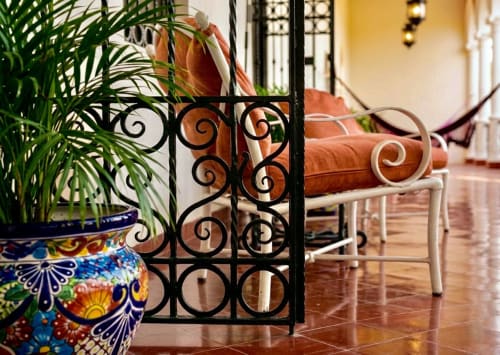 Patio elegante de Villa Merida Boutique Hotel con herrería ornamental, maceta talavera colorida, plantas de palma y terracota