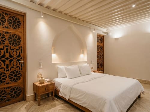 Habitación moderna en Villa Merida Boutique Hotel en Mérida con puertas de madera tallada, ropa de cama blanca e iluminación cálida