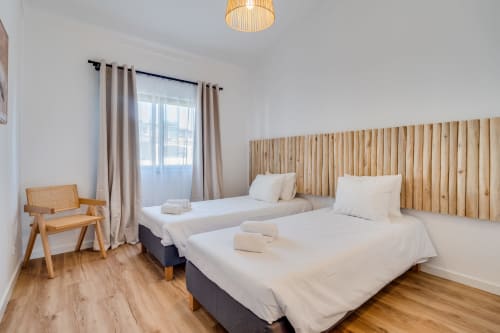Quarto moderno no apartamento AlgarStays Algarve com duas camas, cabeceira de madeira e vistas para o mar