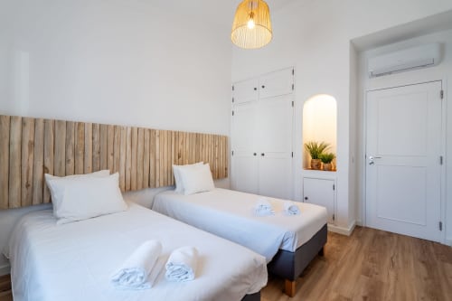 Quarto duplo moderno no apartamento AlgarStays Algarve com cabeceira de madeira, roupa branca, piso de madeira e guarda-roupas embutidos