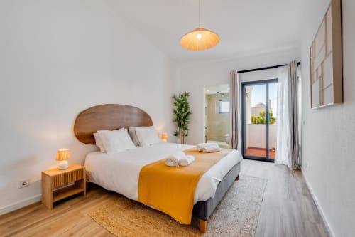 Quarto luminoso no apartamento AlgarStays Algarve com cama de madeira, roupas de cama brancas, varanda com vista para o mar e móveis modernos