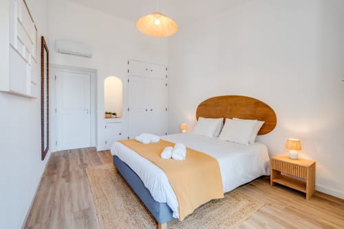 Quarto moderno no apartamento AlgarStays Algarve com cama de madeira, roupa de cama branca, iluminação aquecida e vista para o oceano
