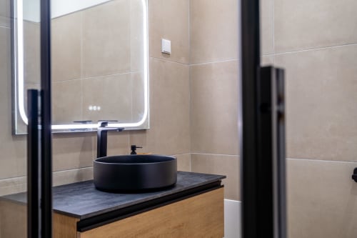 Banheiro moderno no apartamento AlgarStays Algarve com pia circular preta, espelho iluminado e azulejos em tons de bege
