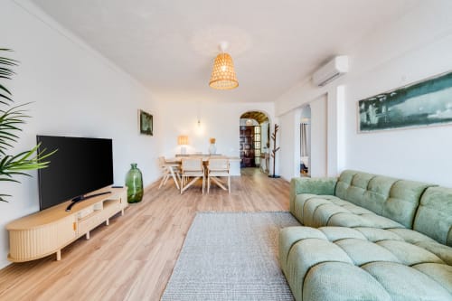 Moderna sala de estar em AlgarStays Retiro com sofá verde, móveis de madeira, TV, área de jantar e iluminação natural