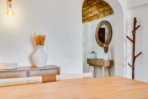Sala de jantar de apartamento moderno no Algarve com mesa de madeira, espelho trançado, flores secas e elementos de design costeiro