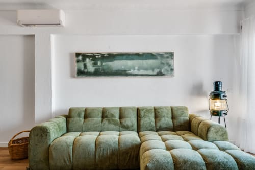 Sala de estar moderna com sofá acolchoado verde, quadro paisagístico, ar-condicionado e luminária de piso em AlgarStays Algarve