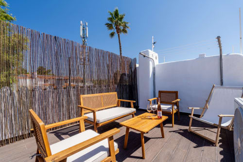 Ensolarada varanda na cobertura com móveis em madeira, tela de privacidade listrada e vistas para o mar no apartamento AlgarStays Algarve