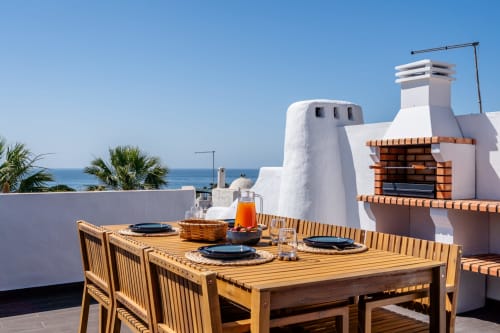 Terraço na cobertura com vista para o oceano em Algarstays Alporchinos, móveis de madeira e churrasqueira integrada