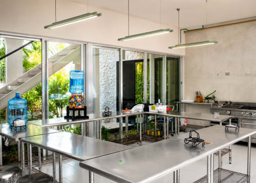 Cocina comercial moderna del hotel boutique Villa Merida con encimeras de acero inoxidable, luces colgantes y jardín