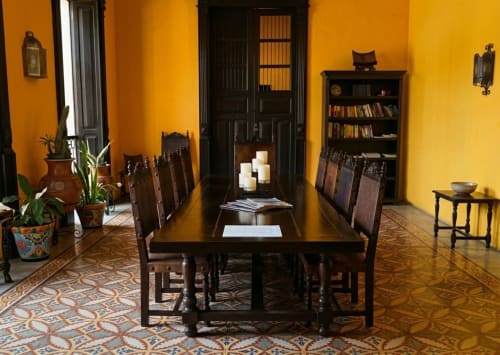 Comedor elegante en Villa Merida Boutique Hotel con paredes amarillas, muebles de madera oscura y azulejos mexicanos coloridos