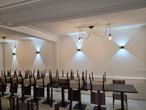 Modern dining room with black chairs, elegant ceiling details, and contemporary wall sconces at STE CATALAUNES, Chalons en