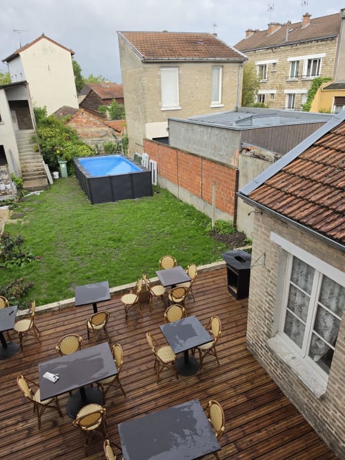 Outdoor terrace with dining tables and chairs at Gîte de la cité Tirlet in Chalons en Champagne, overlooking garden with
