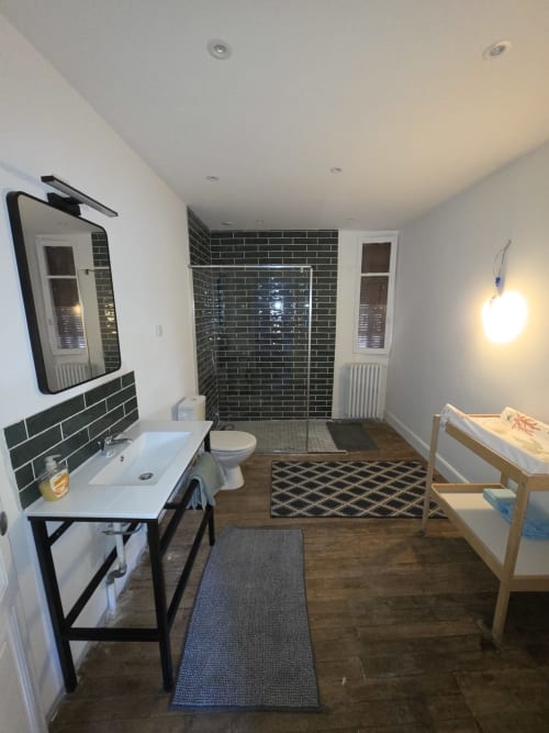 Modern bathroom in Gîte de la cité Tirlet cottage, Chalons en Champagne, featuring black subway tile shower, white sink, and