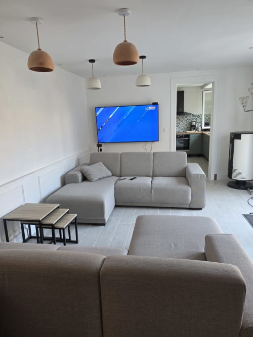 Modern living room at Gîte de la cité Tirlet, Chalons en Champagne, with gray sectional sofa, wall-mounted TV, and pendant
