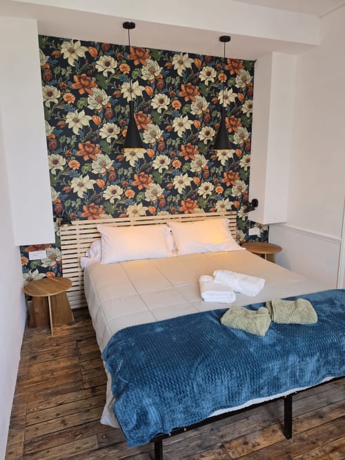 Bedroom at Gîte de la cité Tirlet cottage with floral wallpaper, wooden headboard, and blue bedding in Chalons en Champagne