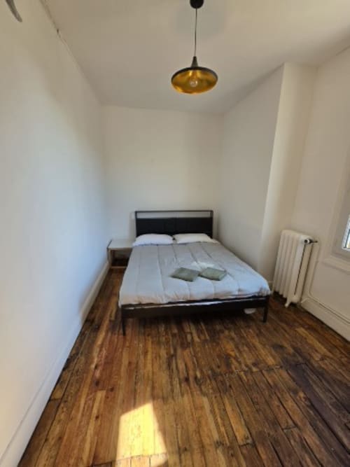 Modern bedroom in Gîte de la cité Tirlet cottage in Chalons en Champagne with wooden floors, pendant light, and radiator