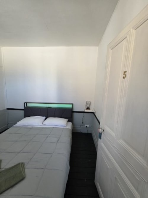 Minimalist cottage bedroom at Ste Catalaunes Chalons en Champagne with modern black headboard bed and white walls.