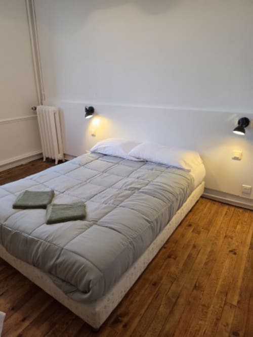 Bedroom at Gîte de la cité Tirlet cottage in Chalons en Champagne with bed, pillows, blanket, and reading lamps