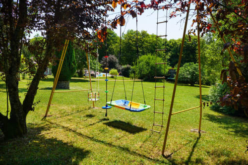 Jardin familial de la villa Maison Héléna avec équipements de fitness extérieur, balançoires et structures d'escalade sur pelouse verdoyante