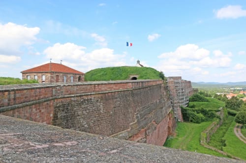 Historic fortress walls and green mound with French flag in Seingbouse, France
