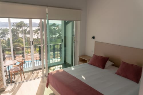 Quarto luminoso com vista para o lago no hotel Monte Horeb em Nadadouro, Portugal, com varanda e comodidades modernas