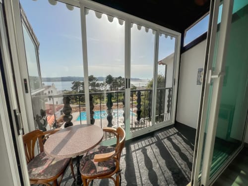 Varanda de quarto com vista para o lago no hotel Monte Horeb, Portugal, com mesa, cadeiras, piscina e vista de água