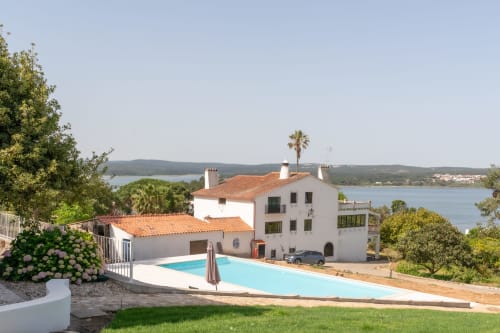 Piscina do hotel Monte Horeb com vista para o lago de Nadadouro, Portugal, com arquitetura de villa branca e jardins