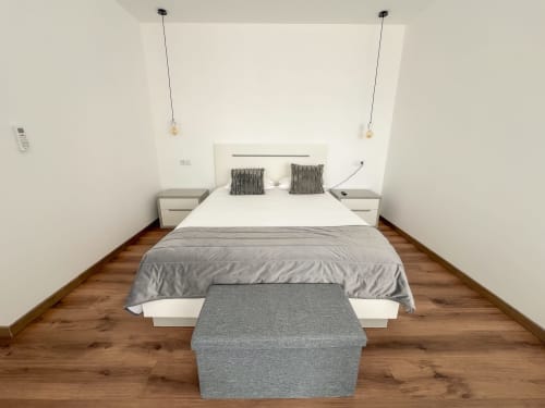 Quarto moderno do hotel Monte Horeb em Nadadouro com cama queen, pisos em madeira, luminárias pendentes e móveis contemporâneos